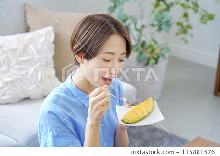 Woman eating melon at home Woman eating melon at home 115881376