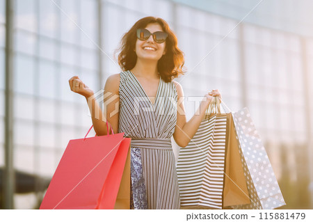 Shopping time. Young woman with shopping bags near the mall. Consumerism, sale, purchases. Shopping time. Young woman with shopping bags near the mall. Consumerism, sale, purchases. 115881479