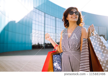 Shopping time. Young woman with shopping bags near the mall. Consumerism, sale, purchases. Shopping time. Young woman with shopping bags near the mall. Consumerism, sale, purchases. 115881486