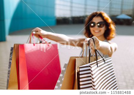 Shopping time. Young woman with shopping bags near the mall. Consumerism, sale, purchases. 115881488