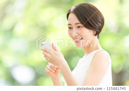 Middle-aged woman holding a smartphone, fresh greenery 115881745