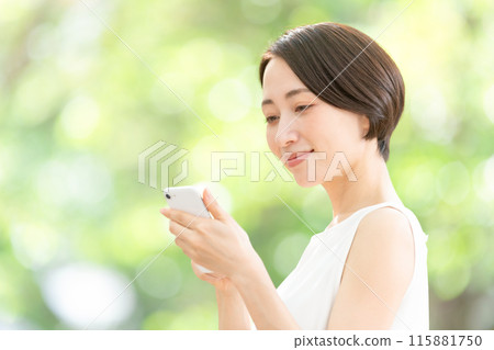 Middle-aged woman holding a smartphone, fresh greenery 115881750