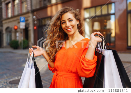 Happy woman with shopping bags walking on sunny street. Concept of lifestyle, buying, selling. Happy woman with shopping bags walking on sunny street. Concept of lifestyle, buying, selling. 115881841