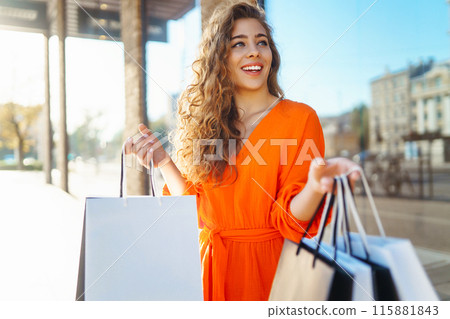 Happy woman with shopping bags walking on sunny street. Concept of lifestyle, buying, selling. 115881843