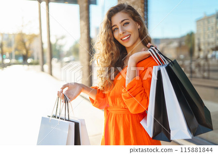 Happy woman with shopping bags walking on sunny street. Concept of lifestyle, buying, selling. 115881844