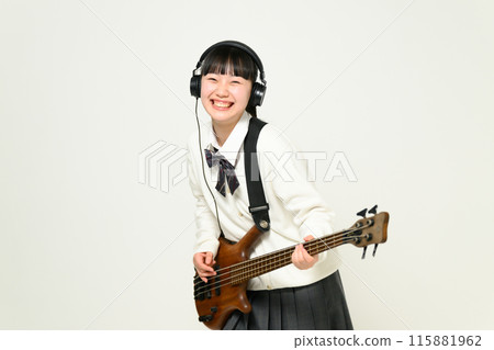 A high school girl wearing headphones and playing the bass A high school girl wearing headphones and playing the bass 115881962