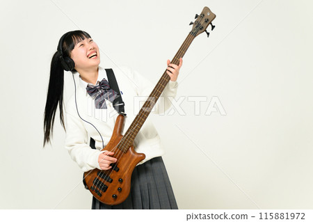 A high school girl wearing headphones and playing the bass A high school girl wearing headphones and playing the bass 115881972