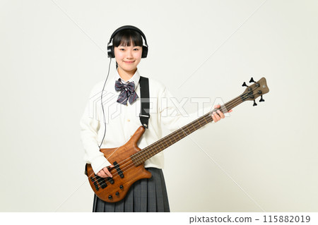 A high school girl wearing headphones and playing the bass A high school girl wearing headphones and playing the bass 115882019