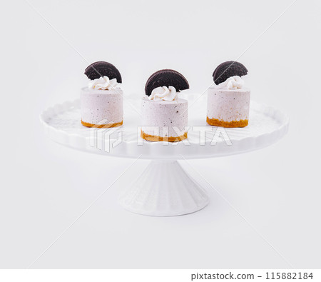 Elegant mini cheesecakes with cookie garnish on white stand 115882184