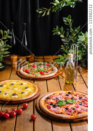 Assorted wood-fired pizzas and wine on rustic wooden table 115882212