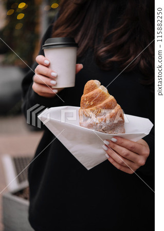 Woman holding fresh pastry and coffee outdoors 115882250