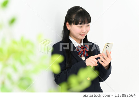A high school girl leaning against a wall and operating a smartphone A high school girl leaning against a wall and operating a smartphone 115882564