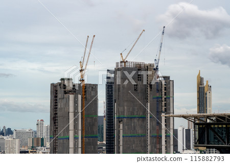 Timelapse view of big construction cranes working on top of high-rise buildings in Bangkok, Thailand with moving clouds and high-rises buildings in background 115882793