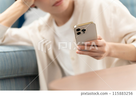 A woman in her 40s looking at her smartphone A woman in her 40s looking at her smartphone 115883256
