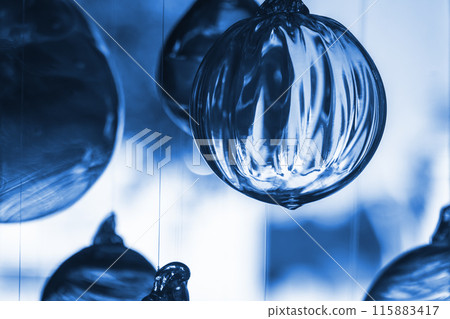 Glass balls hang in front of bright window, close up blue toned photo Glass balls hang in front of bright window, close up blue toned photo 115883417