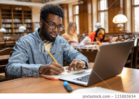 Dark-skinned young man working online in the library 115883634