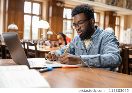 Dark-skinned young man working online in the library 115883635