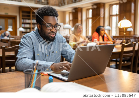 Dark-skinned young man working online in the library 115883647