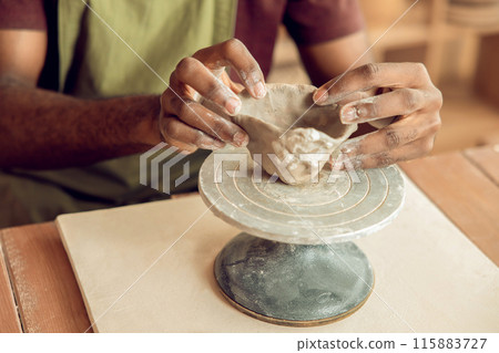 Close up of mans hands molding a shape of clay Close up of mans hands molding a shape of clay 115883727