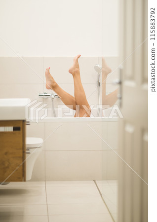 Woman having a bath and raising her legs to the air Woman having a bath and raising her legs to the air 115883792