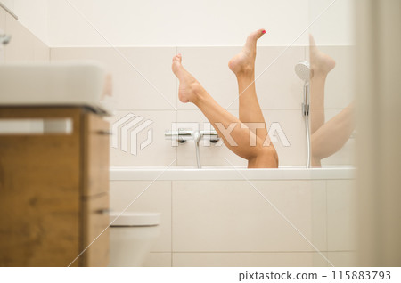 Woman having a bath and raising her legs to the air Woman having a bath and raising her legs to the air 115883793