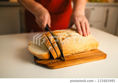 Homemade sourdough bread. Woman hands cuts the bread on cutting board. Handcrafted. Wooden cutting board. Homemade sourdough bread. Woman hands cuts the bread on cutting board. Handcrafted. Wooden cutting board. 115883995
