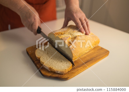 Homemade sourdough bread. Woman hands cuts the bread on cutting board. Handcrafted. Wooden cutting board. Homemade sourdough bread. Woman hands cuts the bread on cutting board. Handcrafted. Wooden cutting board. 115884000
