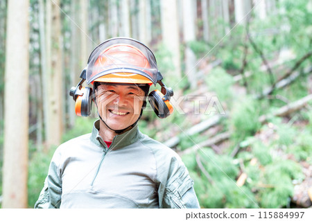 A forest worker looks at me with a big smile, with the felled area in the background. A forest worker looks at me with a big smile, with the felled area in the background. 115884997