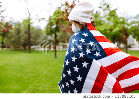 Girl in protective sterile medical mask and with american flag in hand. Quarantine city. Covid -19. 115885105