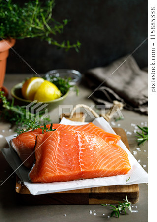 Salmon. Fresh raw salmon fish fillet with cooking ingredients, herbs and lemon on dark background 115885338