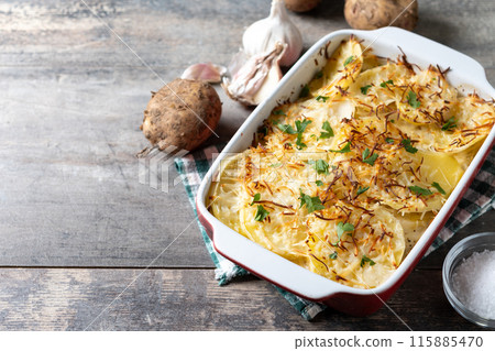 Potato gratin baked with cream and cheese on wooden table Potato gratin baked with cream and cheese on wooden table 115885470