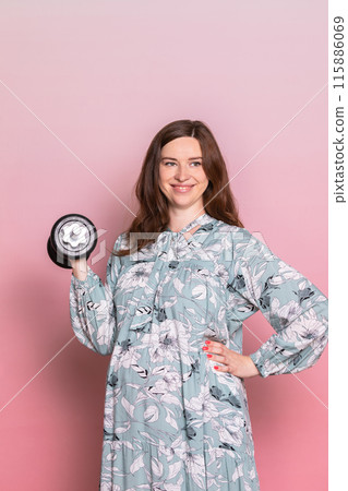 Happy Pregnant Woman Lifting Dumbbell in Floral Dress 115886069