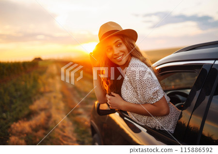 Woman is resting and enjoying sunset in car. Summer trip. Lifestyle, travel, tourism, active life. Woman is resting and enjoying sunset in car. Summer trip. Lifestyle, travel, tourism, active life. 115886592