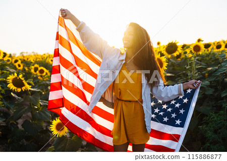 Woman proudly hold waving american USA flag in in the sunflower field. Independence Day, 4th July. Woman proudly hold waving american USA flag in in the sunflower field. Independence Day, 4th July. 115886877