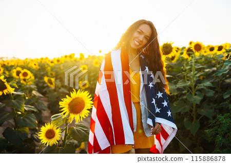 Woman proudly hold waving american USA flag in in the sunflower field. Independence Day, 4th July. Woman proudly hold waving american USA flag in in the sunflower field. Independence Day, 4th July. 115886878
