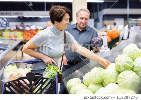 Husband and wife choose and buy fresh cabbage in grocery store 115887270