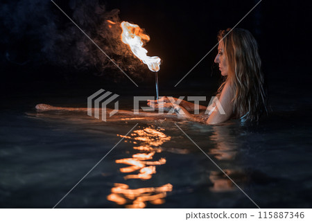 Caucasian woman dancing with fire in the water. Fire show at sea. Acrobatics on the beach. Yoga and relaxation at sunset. Spectacular circus performance. model body. High quality FullHD footage.  115887346