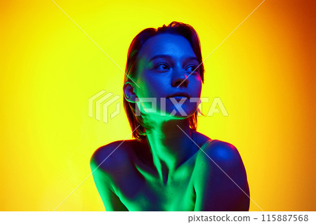 Portrait of young woman with bare shoulders posing looking away in neon light against gradient studio background. Well-cared-for skin. 115887568
