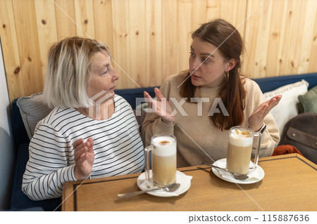 Group women enjoying fun conversation with cup of coffee at indoor restaurant. Lifestyle concept, two people. Two female sit in the cafeteria, chatting and gossiping 115887636