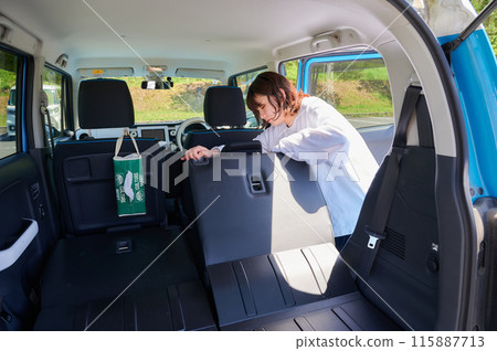 Woman folding down the back seat of a car, leisure, travel Woman folding down the back seat of a car, leisure, travel 115887713
