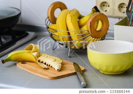 Peeled and sliced banana on a cutting board. 115888144
