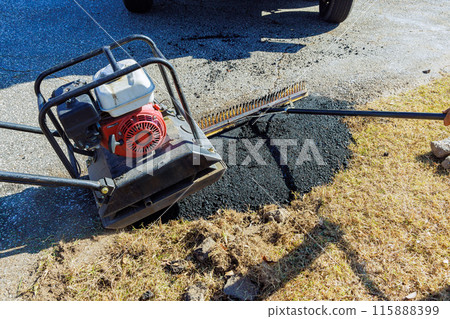 In repair of parking lot, asphalt is tamped manually using tamping compacting vibratory 115888399