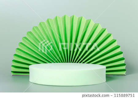 A green paper fan is placed on a white pedestal 115889751