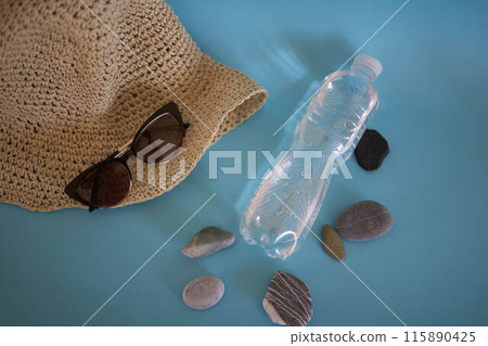 straw hat, sunglasses, bottle of water, sun spray, pebbles on a colored background straw hat, sunglasses, bottle of water, sun spray, pebbles on a colored background 115890425