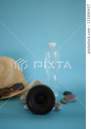 lens, straw hat, sunglasses, bottle of water, sunscreen spray, pebbles on a colored background lens, straw hat, sunglasses, bottle of water, sunscreen spray, pebbles on a colored background 115890427