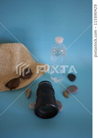 lens, straw hat, sunglasses, bottle of water, sunscreen spray, pebbles on a colored background lens, straw hat, sunglasses, bottle of water, sunscreen spray, pebbles on a colored background 115890429