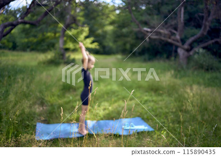 little 5-year-old girl in a black minimalist overall does gymnastics in the garden, outdoors little 5-year-old girl in a black minimalist overall does gymnastics in the garden, outdoors 115890435