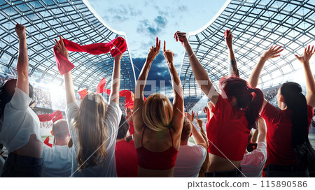 Vibrant crowd of enthusiastic sports fans raises their arms and waves red scarves in celebration against modern stadium with clear sky above. Vibrant crowd of enthusiastic sports fans raises their arms and waves red scarves in celebration against modern stadium with clear sky above. 115890586