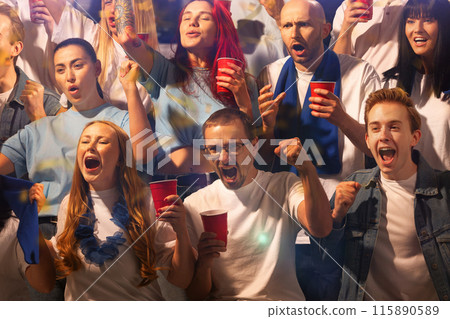 Excited crowd sitting on tribunes and watching sport game with scarfs to support their favorite team. People drinks beer and shouting. 115890589