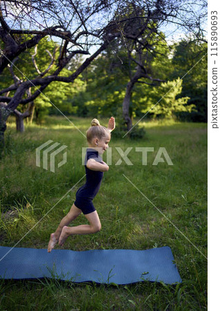 little 5-year-old girl in a black minimalist overall does gymnastics in the garden, outdoors little 5-year-old girl in a black minimalist overall does gymnastics in the garden, outdoors 115890693